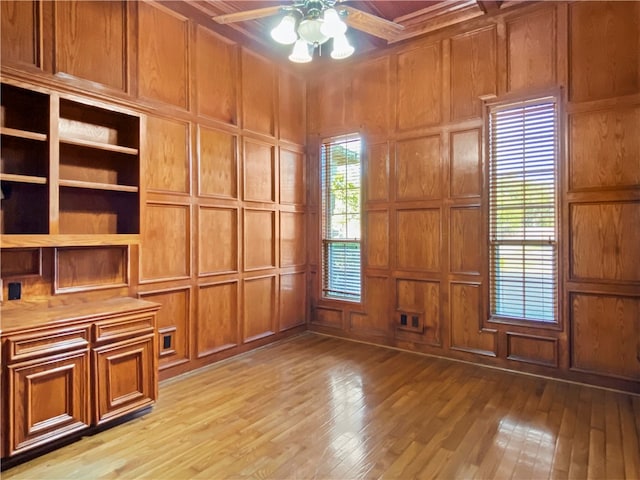 interior space featuring light wood-type flooring, wood walls, and ceiling fan