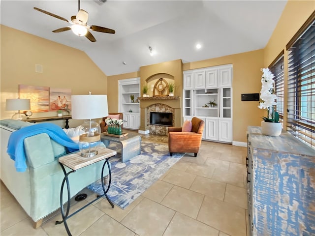 living room with ceiling fan, light tile patterned floors, a stone fireplace, built in features, and vaulted ceiling