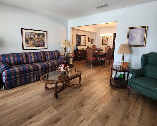 living room featuring a chandelier, light wood-type flooring, and visible vents