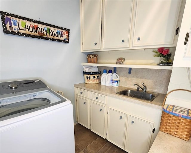 laundry area with dark tile patterned floors, cabinet space, a sink, and washer / dryer