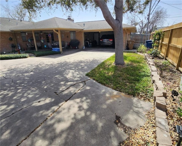 exterior space featuring driveway, fence, and brick siding