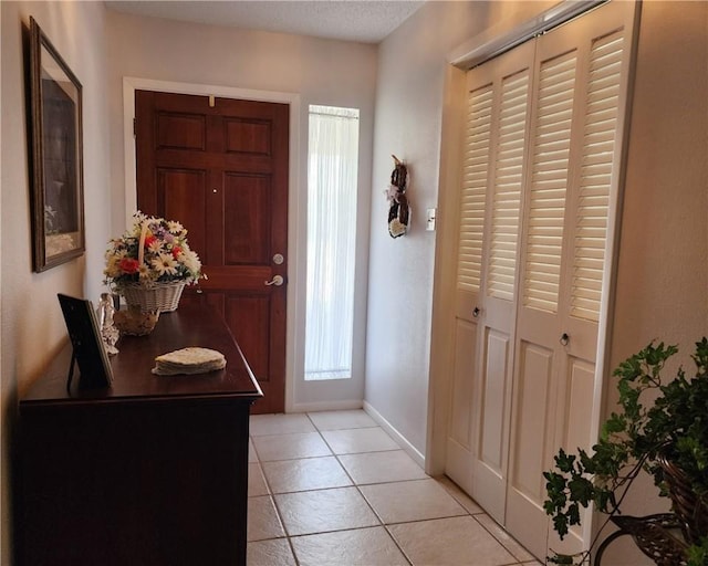 foyer entrance featuring light tile patterned flooring and baseboards