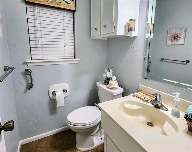 half bath featuring toilet, vanity, baseboards, and a textured wall