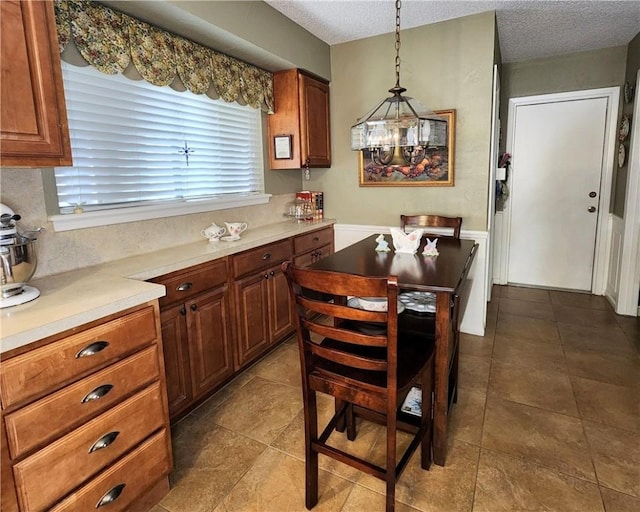 kitchen with brown cabinets, pendant lighting, light countertops, and a textured ceiling