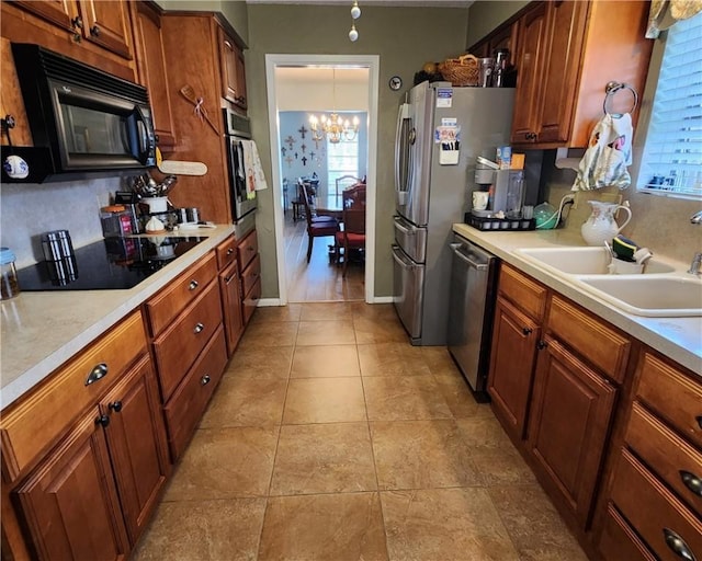 kitchen featuring brown cabinets, a sink, light countertops, black appliances, and a notable chandelier