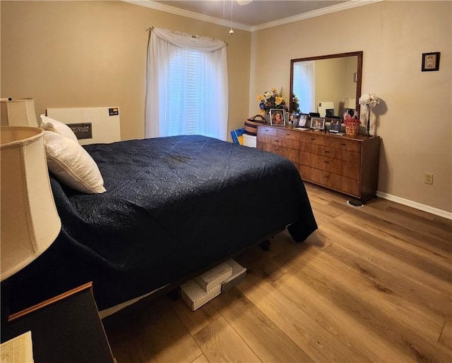 bedroom with baseboards, crown molding, and light wood finished floors