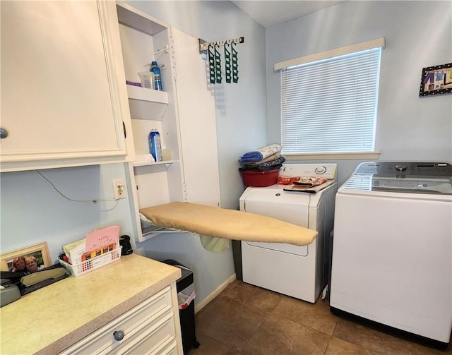 washroom featuring cabinet space, dark tile patterned floors, and independent washer and dryer