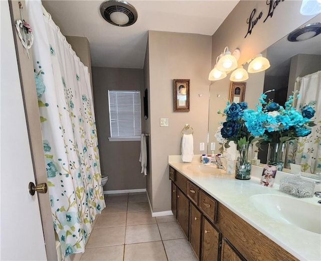 bathroom with double vanity, baseboards, a sink, and tile patterned floors