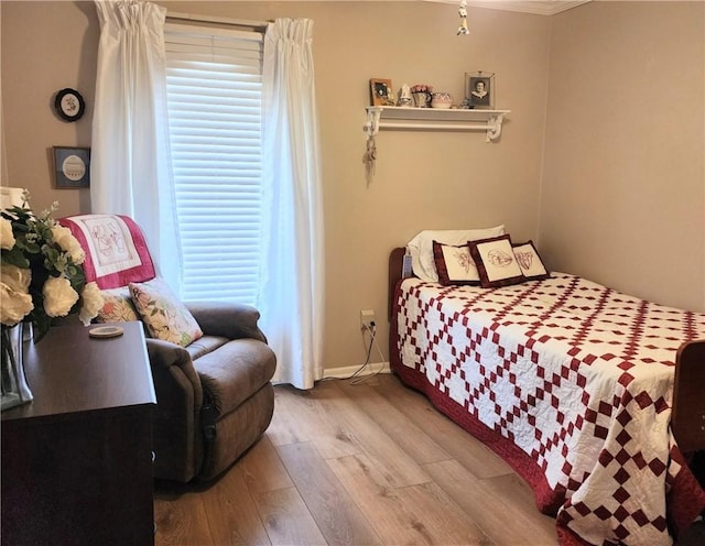 bedroom featuring multiple windows, crown molding, baseboards, and wood finished floors