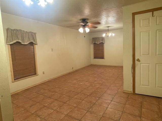 empty room with ceiling fan with notable chandelier and a textured ceiling