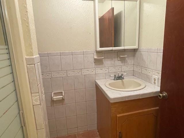 bathroom featuring vanity and tile walls