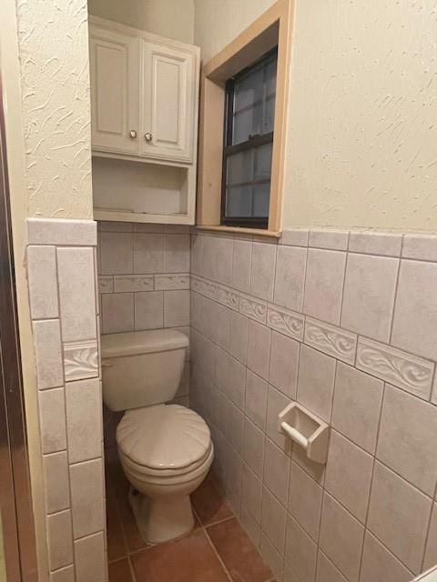 bathroom featuring tile walls, tile patterned floors, and toilet