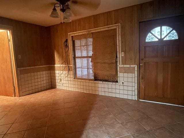 entryway featuring wooden walls, ceiling fan, and plenty of natural light