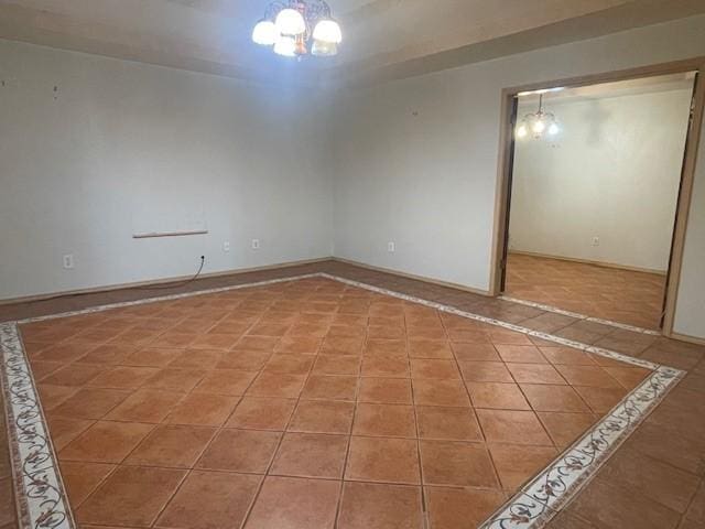 tiled empty room featuring an inviting chandelier