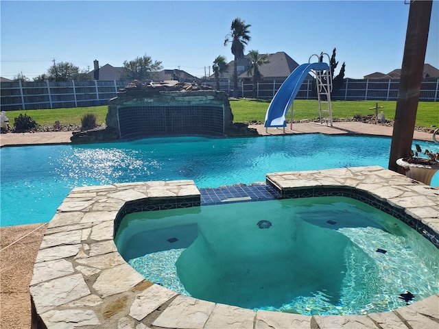 view of pool with an in ground hot tub, a lawn, and a water slide