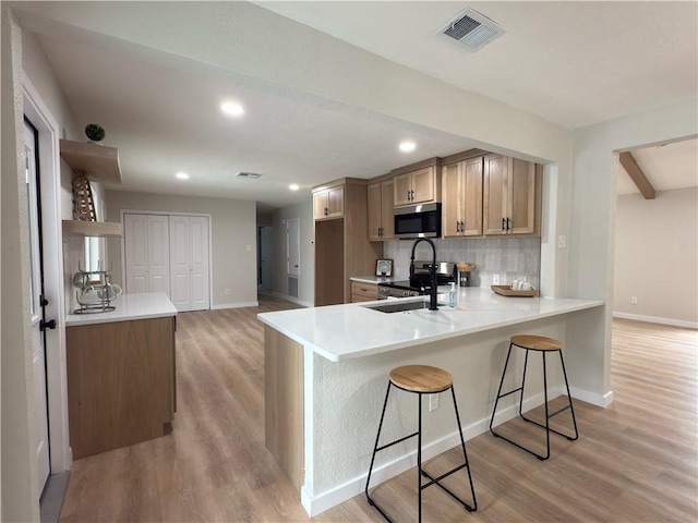 kitchen with light countertops, visible vents, appliances with stainless steel finishes, a sink, and a peninsula