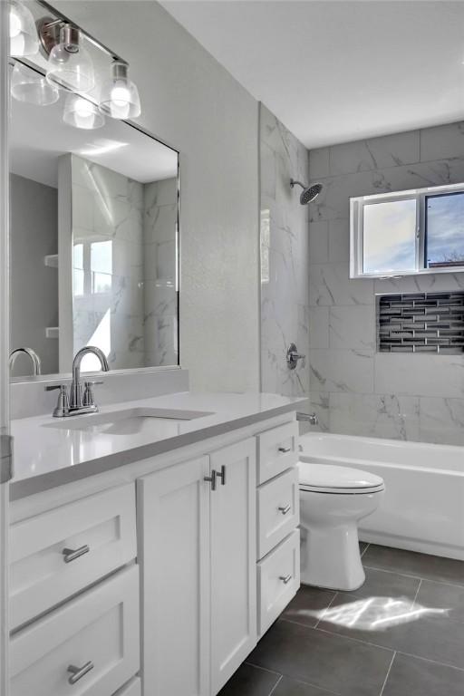 full bathroom featuring tiled shower / bath, vanity, and toilet