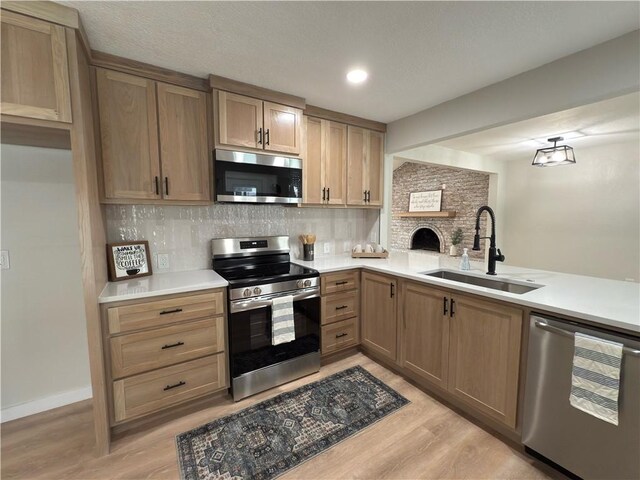 kitchen featuring sink, decorative backsplash, light hardwood / wood-style floors, kitchen peninsula, and stainless steel appliances