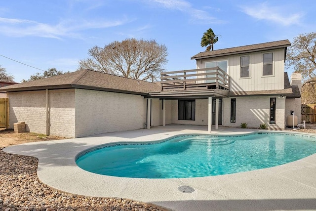 back of property featuring a balcony, a fenced in pool, and brick siding