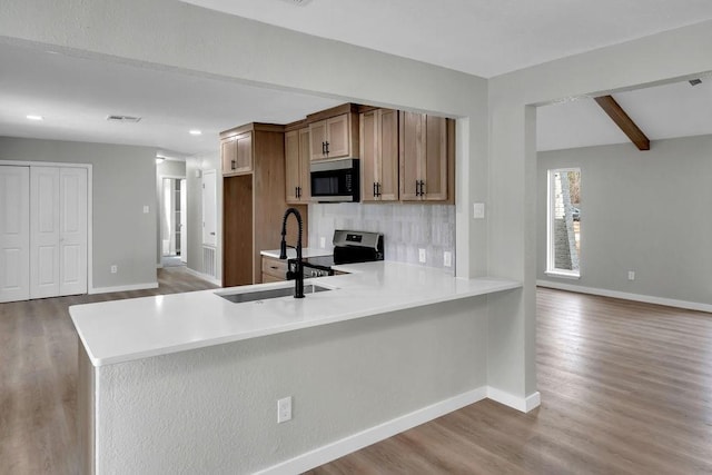 kitchen featuring sink, beam ceiling, light hardwood / wood-style floors, stainless steel electric stove, and kitchen peninsula