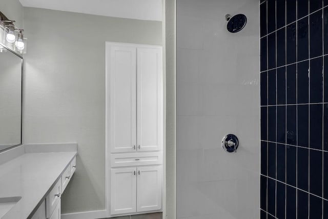 full bathroom with a tile shower and vanity