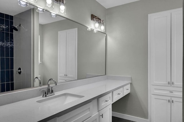 bathroom featuring tiled shower and vanity