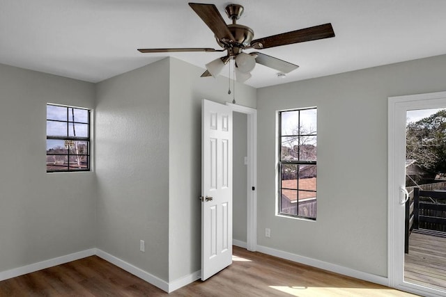 spare room with light wood-type flooring, ceiling fan, and baseboards