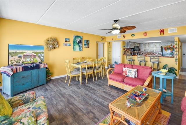 living room featuring hardwood / wood-style floors, ceiling fan, and a textured ceiling