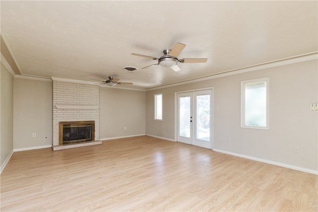 unfurnished living room with french doors, ornamental molding, a fireplace, light wood-type flooring, and ceiling fan