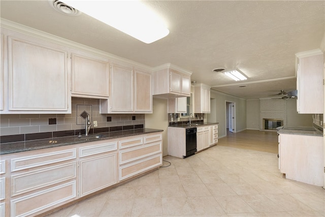 kitchen featuring tasteful backsplash, black dishwasher, sink, a brick fireplace, and ceiling fan