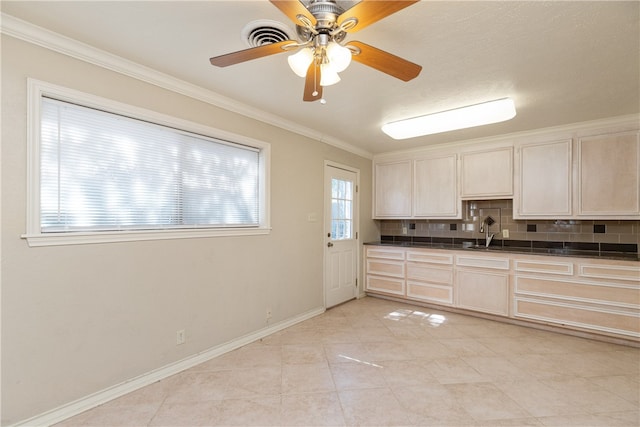 kitchen with sink, light tile patterned floors, ceiling fan, crown molding, and backsplash