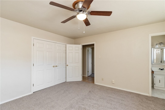 unfurnished bedroom featuring ceiling fan, ensuite bath, a closet, and light colored carpet