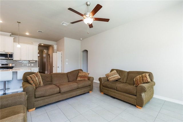 living area with light tile patterned floors, a ceiling fan, visible vents, and baseboards