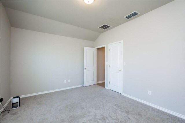 carpeted spare room with vaulted ceiling, baseboards, and visible vents