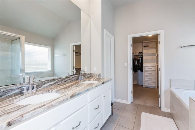 full bath with a sink, double vanity, a bath, and tile patterned floors