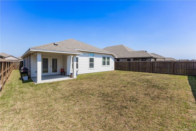 back of house featuring a fenced backyard, french doors, a yard, and roof with shingles