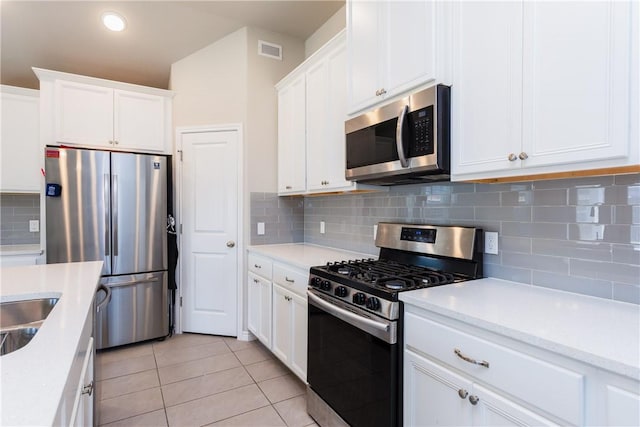 kitchen featuring backsplash, stainless steel appliances, white cabinets, light countertops, and light tile patterned floors