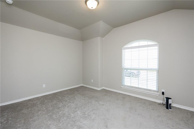 carpeted spare room featuring baseboards and lofted ceiling