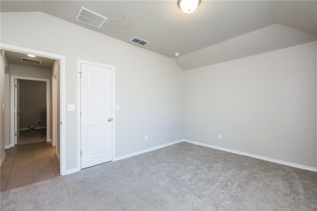 spare room with lofted ceiling, carpet, and visible vents