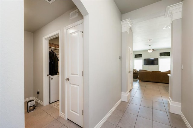 hallway featuring light tile patterned flooring, arched walkways, visible vents, and baseboards