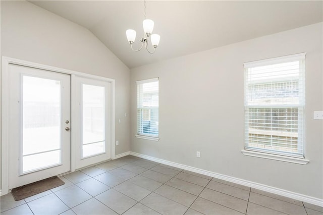 spare room featuring light tile patterned floors, baseboards, lofted ceiling, and a notable chandelier