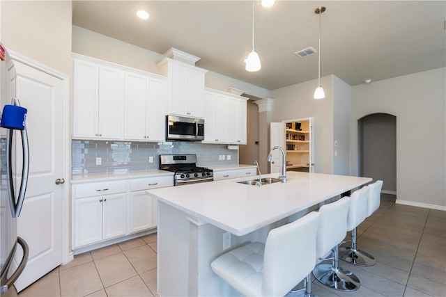 kitchen with light countertops, light tile patterned floors, decorative backsplash, stainless steel appliances, and a sink