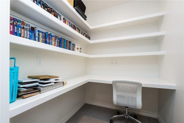 office featuring built in study area, baseboards, and dark tile patterned flooring