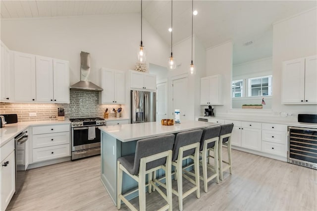 709 Sunrise Ave, Port Aransas, TX 78373 - kitchen with white cabinetry, wall chimney exhaust hood, beverage cooler, and appliances with stainless steel finishes