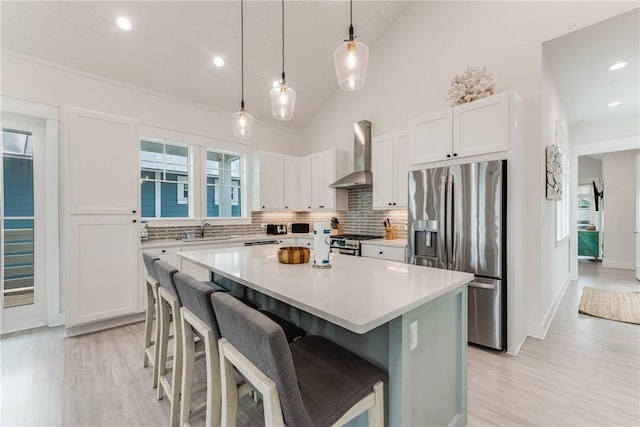 709 Sunrise Ave, Port Aransas, TX 78373 - kitchen with a sink, appliances with stainless steel finishes, white cabinetry, wall chimney range hood, and a center island