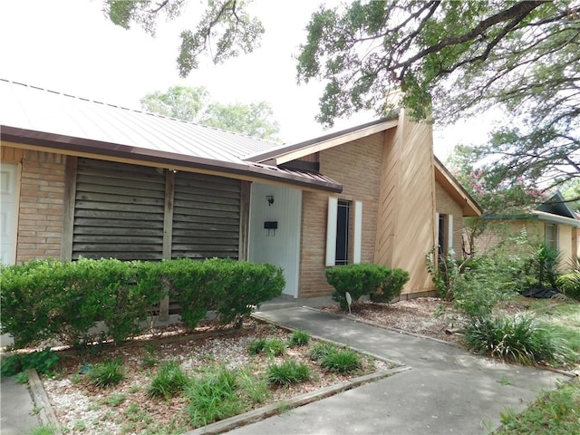 1408 Rose Dr, Alice, TX 78332 - view of front of house with brick siding, a chimney, metal roof, and a standing seam roof