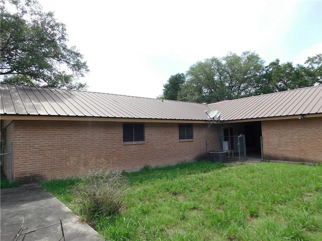 1408 Rose Dr, Alice, TX 78332 - back of property with metal roof, brick siding, and central AC