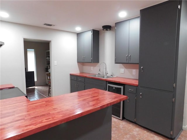 1408 Rose Dr, Alice, TX 78332 - kitchen with wine cooler, a sink, butcher block counters, recessed lighting, and light tile patterned floors