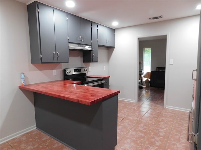 kitchen featuring exhaust hood, light tile patterned floors, kitchen peninsula, and electric stove