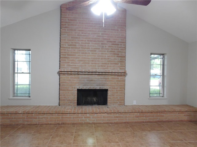 unfurnished living room with a brick fireplace, ceiling fan, tile patterned floors, and vaulted ceiling